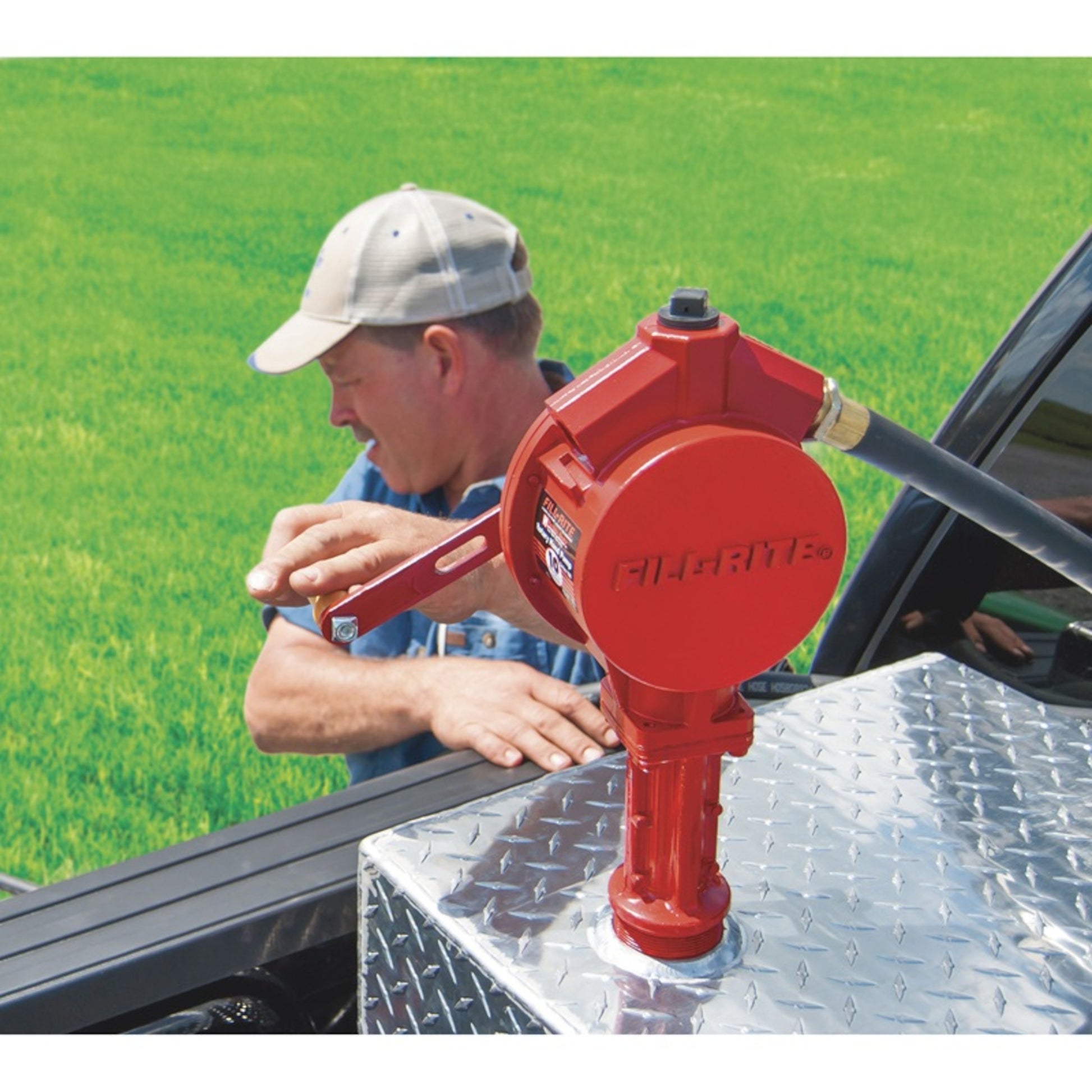 Man using Fill-Rite FR112 rotary hand pump on truck bed fuel tank, red cast iron design with hose for outdoor fuel transfer