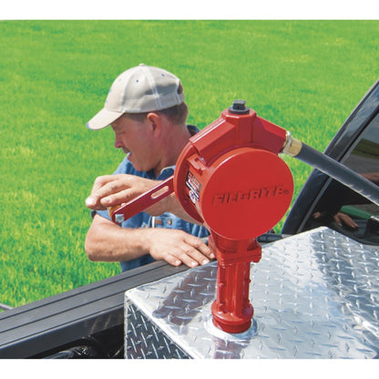 Man using Fill-Rite FR112 rotary hand pump on truck bed fuel tank, red cast iron design with hose for outdoor fuel transfer