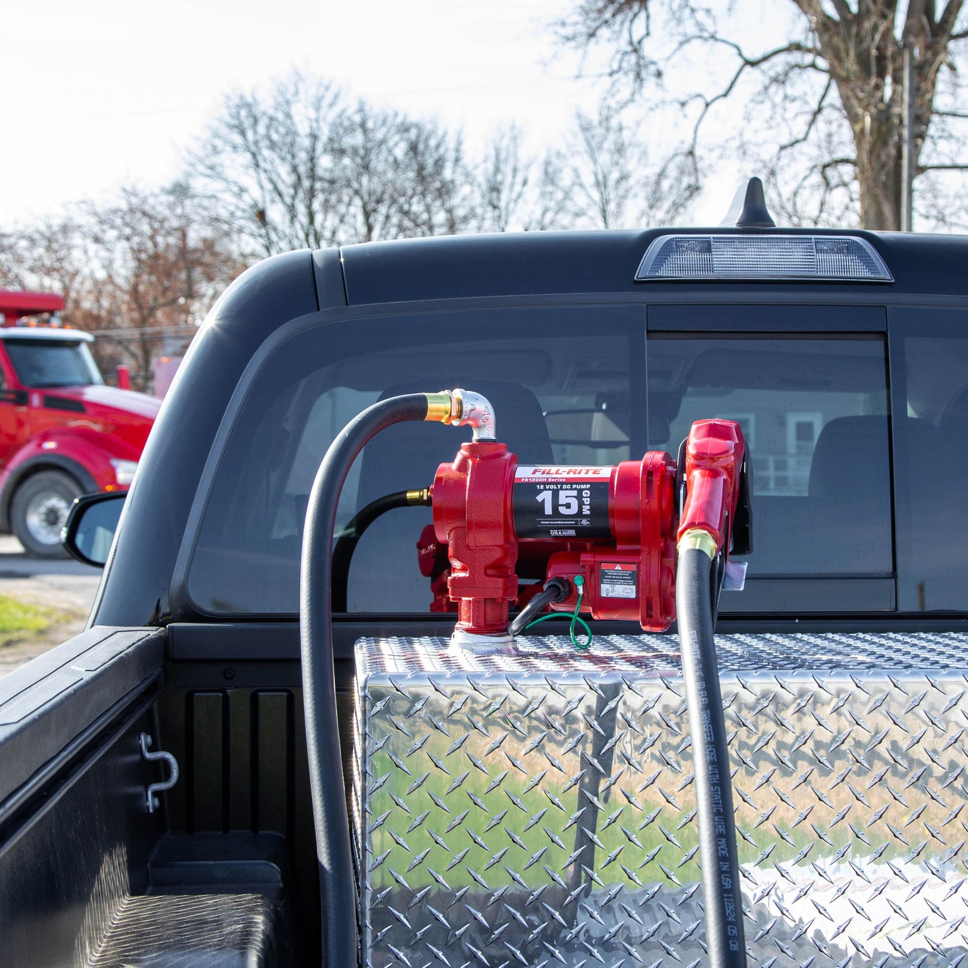 Fill-Rite FR1210HA 12V 15 GPM fuel pump installed in truck bed tank: person using automatic gasoline nozzle for convenient transfer in outdoor setting.